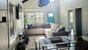A living room with a sectional sofa, a dining table, and a ceiling fan.