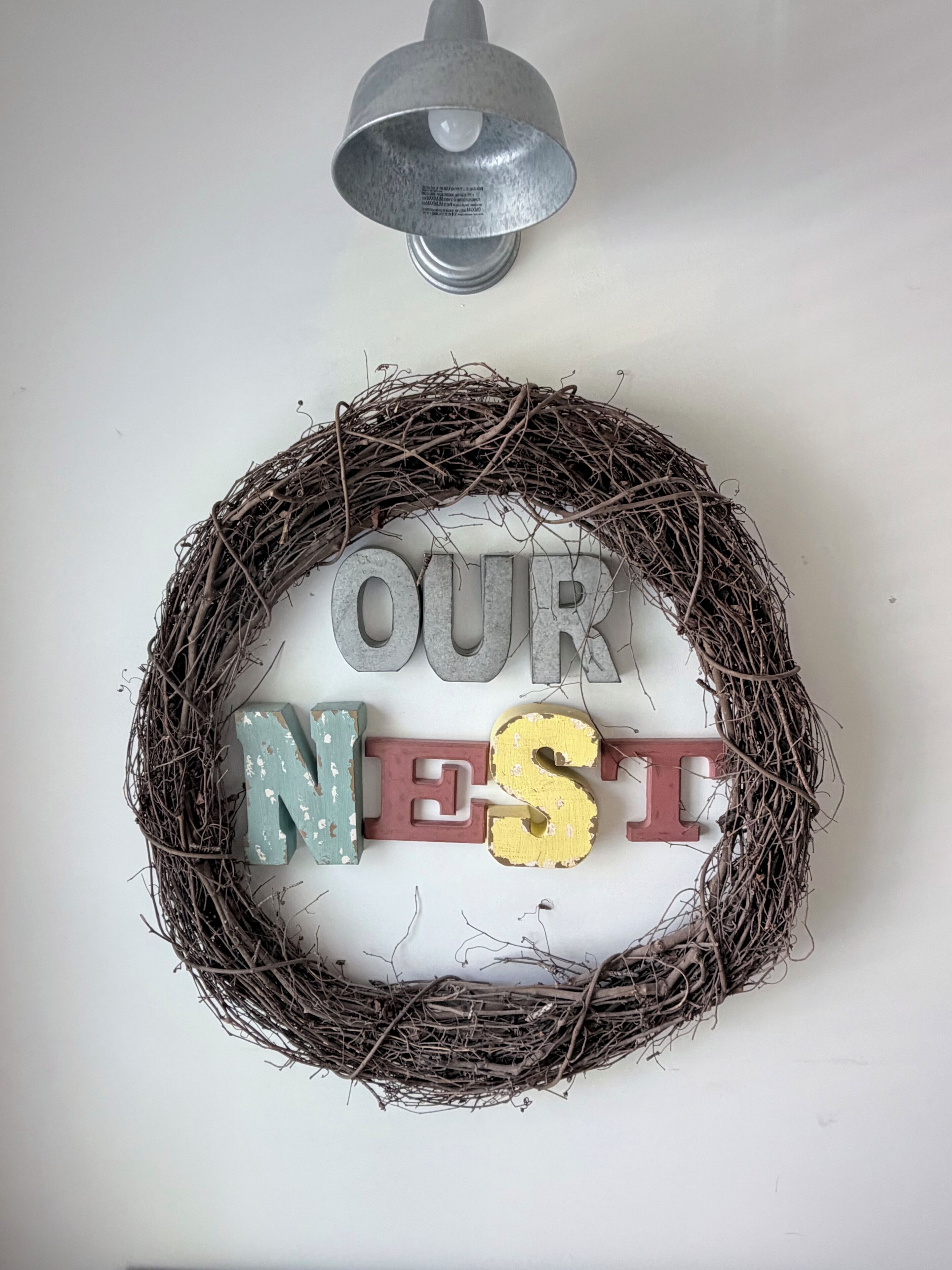 A decorative wreath with the words 'OUR NEST' on a wall.