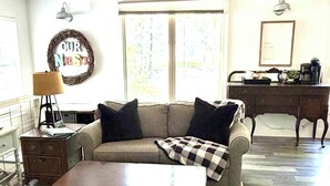 A living room with a sofa, a coffee table, a rug, a desk, and a lamp. - Our Nest, a well loved quiet retreat in Foxwood Hills Resort near Lake Hartwell. (Westminster)