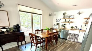 A dining area with a wooden table and chairs, a coffee maker, and a window with a view of trees. - Our Nest, a well loved quiet retreat in Foxwood Hills Resort near Lake Hartwell. (Westminster)