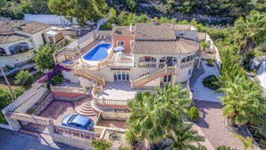 En stor, fleretages villa med swimmingpool, flere balkoner og en anlagt have.