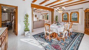 Un espace repas avec une grande table, des chaises en bois et un tapis à motifs.