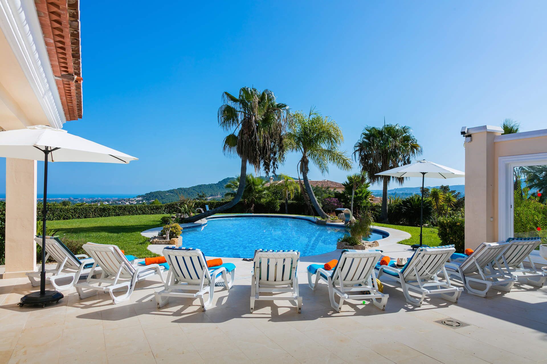 A poolside area with lounge chairs, umbrellas, and a view of the ocean.
