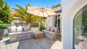 A modern outdoor seating area with two sofas and a table, surrounded by a wooden deck and a large umbrella. - Villa Tomillo by Villa Plus (Jávea)