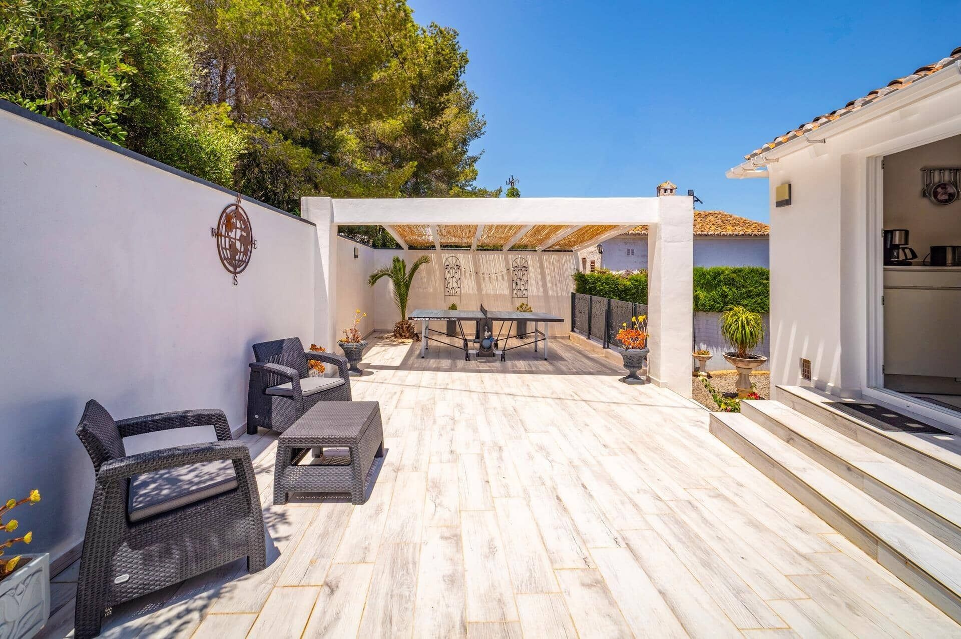 A patio with outdoor furniture, a pergola, and a view of a building with a tiled roof.