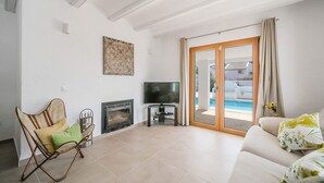 Un salon avec une cheminée, un téléviseur, un canapé et une vue sur une piscine.