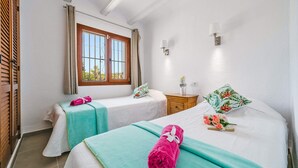 Une chambre d’hôtel avec deux lits, une fenêtre avec des rideaux, une table de chevet et une lampe fixée au mur.