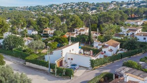 Un quartier résidentiel avec des maisons blanches, dont certaines sont surmontées de toits en tuiles, entouré de verdure et d’arbres.