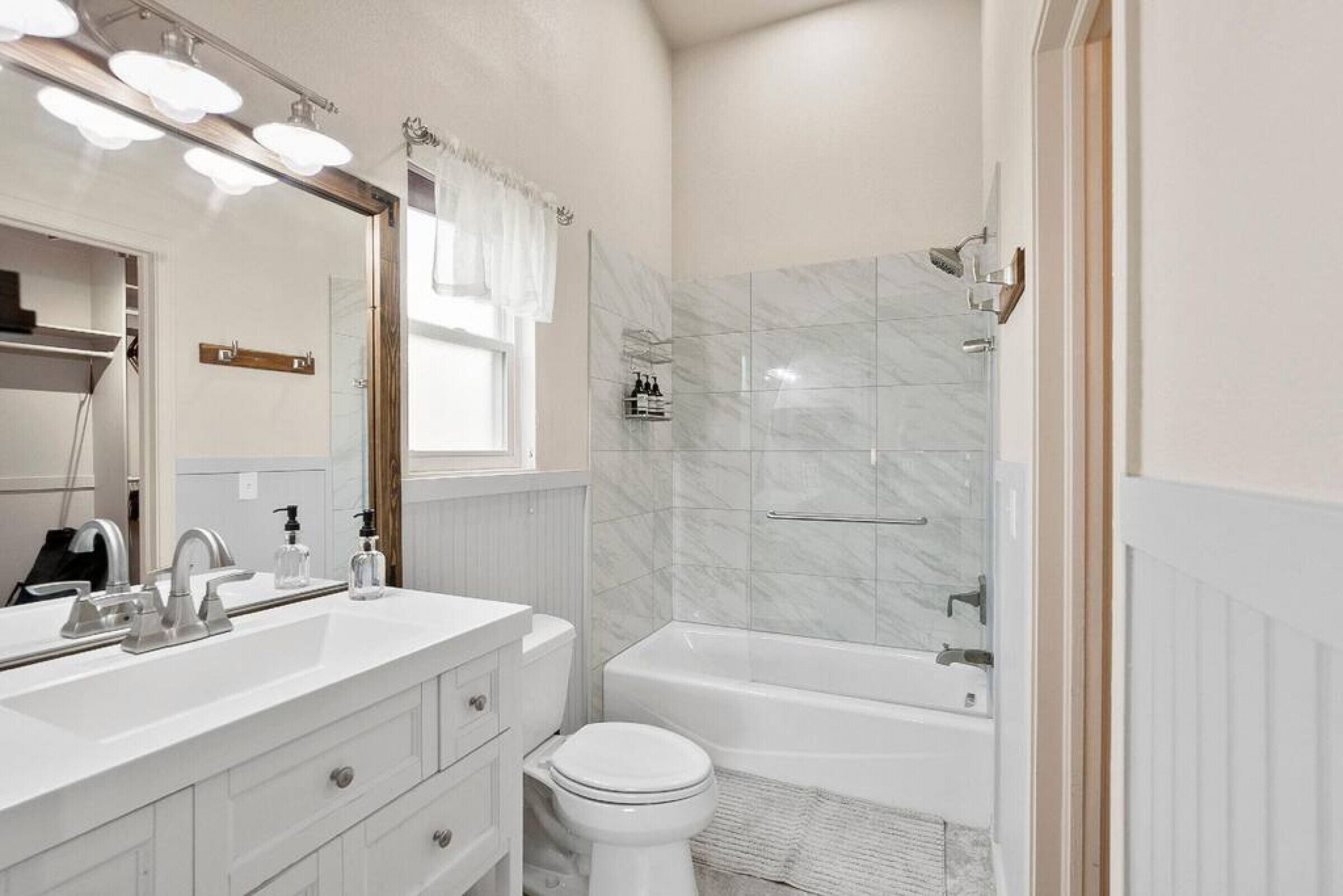 A bathroom with a white vanity, a toilet, a bathtub, and a shower area.