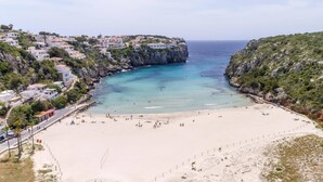 Une ville côtière dotée d’une plage de sable, de falaises rocheuses et de bâtiments construits sur le flanc de la colline.
