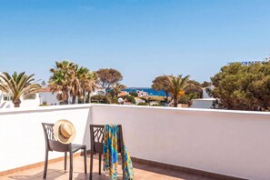 A terrace with two chairs, one with a hat, and a colorful cloth draped over another chair.