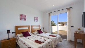 A hotel room with two beds, a balcony, and a view of the sea.