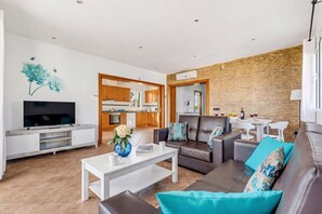 A modern living room with a flat-screen TV, a white coffee table, and a sofa with teal cushions. - Villa Natasha by Villa Plus (Los Delfines)