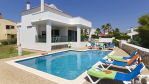 A modern house with a swimming pool and lounge chairs.