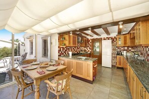 Eine geräumige Küche mit Holzausstattung, einer zentralen Kochinsel und einem Essbereich mit Tisch und Stühlen.