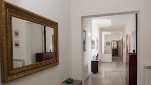 Un pasillo con un espejo grande y ornamentado, una mesita con un mantel rojo y un armario.