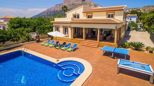 A pool area with lounge chairs, a table, and a ping pong table.