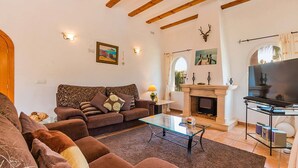 Ein Wohnzimmer mit einer Sofagarnitur, einem Glastisch, einem Kamin und einem Fernseher.