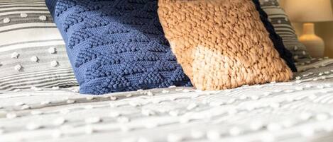 A bed with two pillows, one blue and one beige, on a striped bedspread.