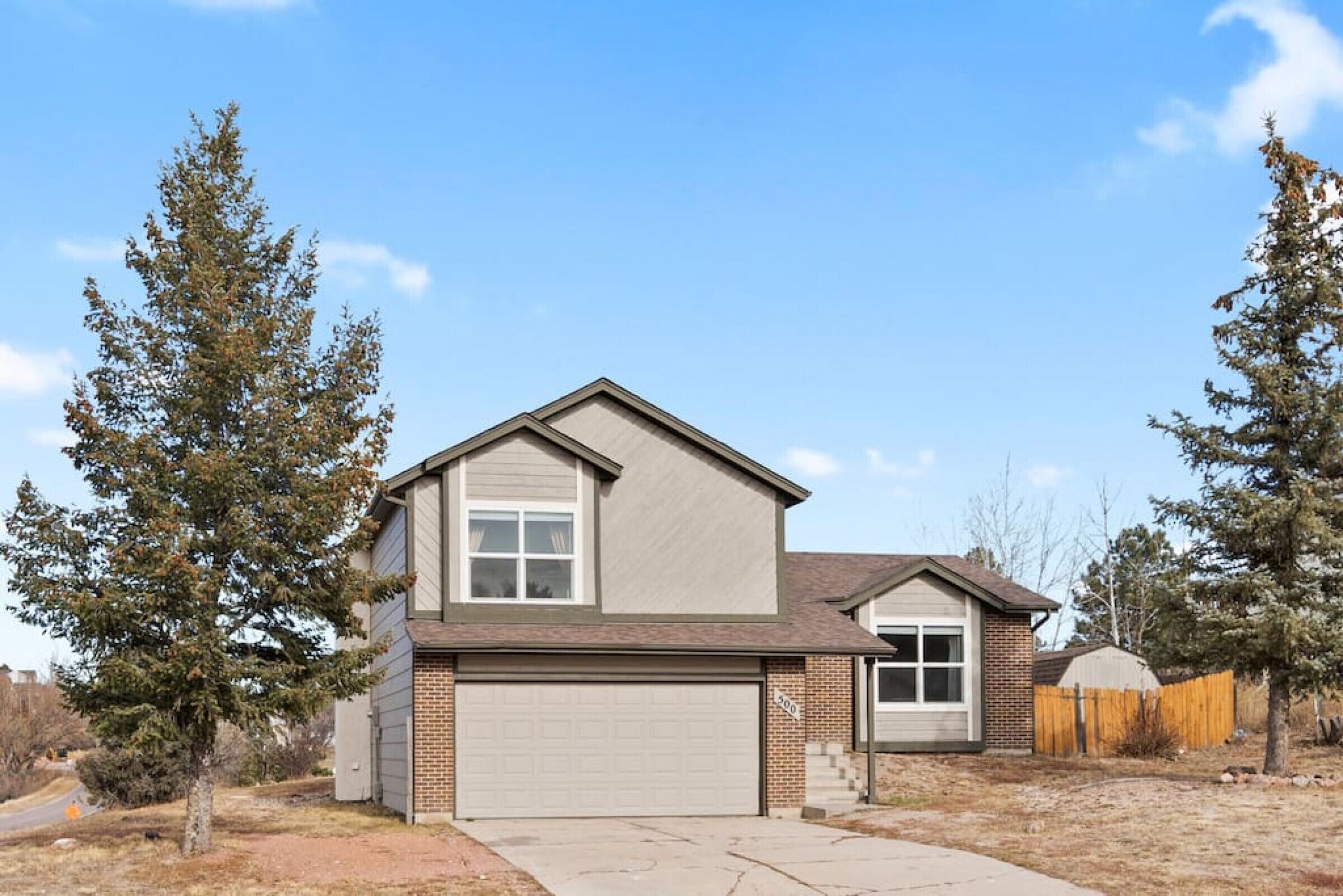 A single-story house with a garage, a small attached shed, and a fenced backyard.