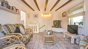 A cozy living room with wicker furniture, a fireplace, and a television. - Villa Jessie by Villa Plus (Montgo de Toscamar)