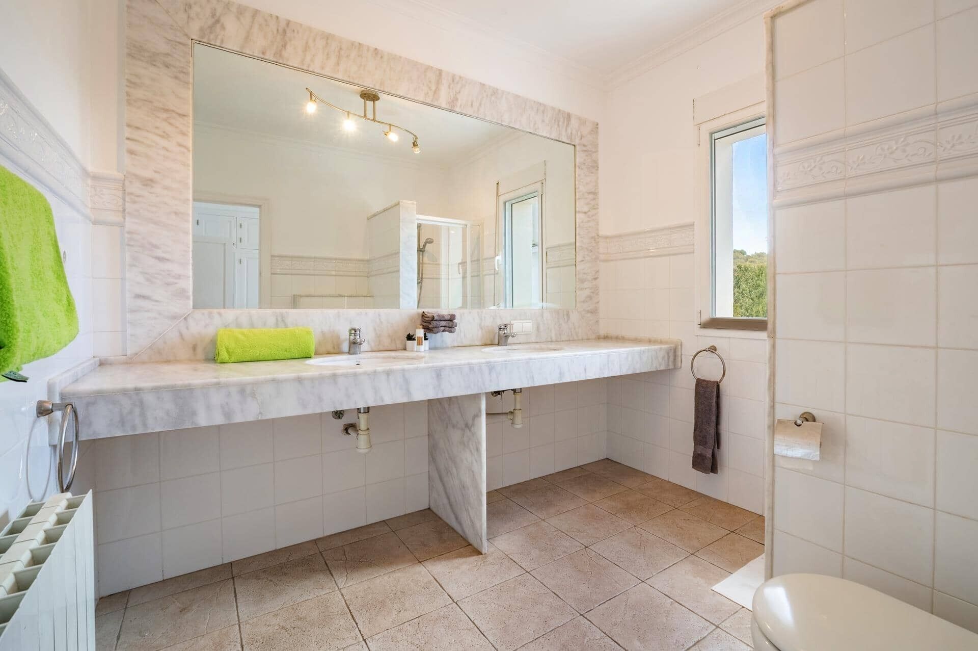 Une salle de bain avec un grand miroir, un double vasque et des toilettes.