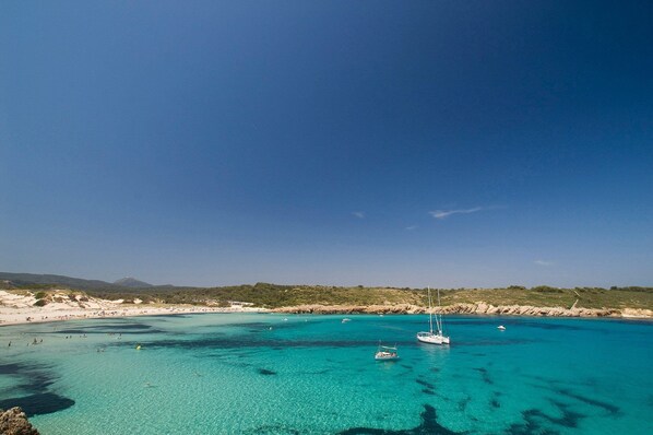 A coastal area with clear turquoise waters, boats, and a sandy beach.