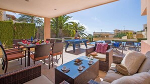 Uma área de terraço ao ar livre com móveis de vime, mesa de bilhar e uma mesa de jantar posta para uma refeição.