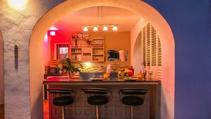 Una cocina con barra, que incluye una isla central con taburetes, un microondas y diversos electrodomésticos.