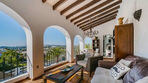 Amplia sala de estar con balcón y vistas panorámicas, que incluye un sofá, sillones de mimbre y una mesa de centro de madera.