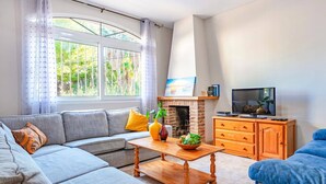 A living room with a grey sofa, a wooden coffee table, a TV, and a fireplace. - Villa Belinda by Villa Plus (Calp)