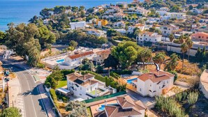 An aerial view of Villa Belinda, featuring a mix of residential buildings, a swimming pool, and a road with a pedestrian crossing. - Villa Belinda by Villa Plus (Calp)