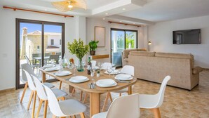 A dining area with a round table, white chairs, and a potted plant. - Villa Catorce Flores by Villa Plus (Teulada)