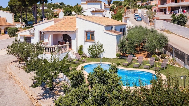 Uma villa com piscina, rodeada por vegetação e vista desimpedida do bairro.