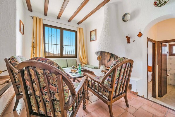 Un comedor con sillas de madera y una mesa, una ventana con cortinas y una chimenea.