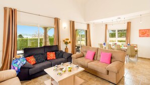 A spacious living room with two sofas, a dining table, and large windows offering a view of the outdoors. - Villa Elefante by Villa Plus (Jávea)