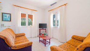 A room with two patterned sofas, a wooden coffee table, a television on a stand, and windows with curtains. - Villa Fresa Blanca by Villa Plus (El Tosalet)