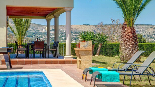 Zona exterior coberta amb piscina, gandules i taula amb cadires.