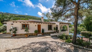 Una vila d'estil mediterrani amb teulada de rajola, parets de pedra i un camí de grava.