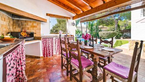 Cuina amb paret de maó, sostre de fusta i finestra amb vista a un jardí.