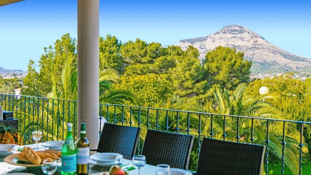 Un espace de restauration en plein air avec une table dressée pour un repas, offrant une vue sur un paysage montagneux.