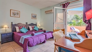 A bedroom with two beds, a desk, a chair, and a balcony with a view of greenery. - Villa Mar Flores by Villa Plus (Teulada)