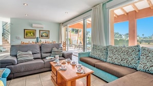 A spacious living room with a grey sofa, a teal sofa, and a wooden coffee table with tea cups. There are two framed pictures on the wall and a staircase in the background. - Villa Mar Flores by Villa Plus (Teulada)