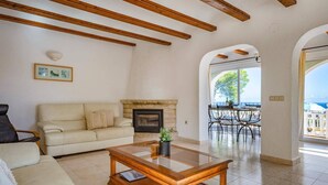 A living room with a sofa, a coffee table, a fireplace, and a view of the outside. - Villa Moggalatto by Villa Plus (Calp)
