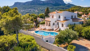 A white villa with a swimming pool, surrounded by greenery and mountains in the background. - Villa Moggalatto by Villa Plus (Calp)