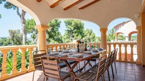 Zona de menjador a l'aire lliure coberta, amb una taula preparada per a sis persones i cadires al voltant.