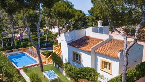 Una vila amb piscina, taula de bitlles i jardí ben cuidat.