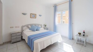 Un dormitorio con cama, mesitas de noche, cortinas en la ventana y vista al exterior.