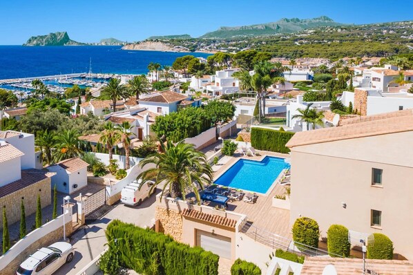 A coastal residential area with a swimming pool, white buildings, and a view of the sea.