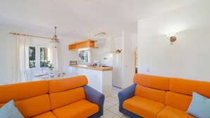 A living room with two orange sofas, a kitchen area with a wooden counter, and a dining area with a table and chairs. - Villa Rosa Blanca by Villa Plus (El Tosalet)
